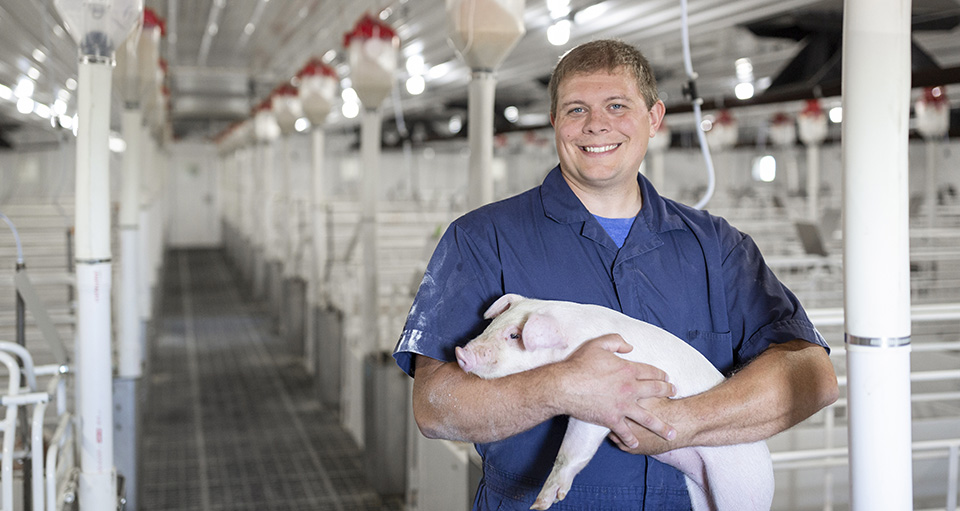 Dr. Bents smiling and holding a piglet